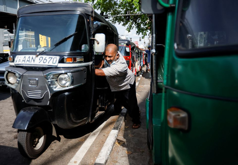 An auto driver pushes his auto as he runs out of fuel while waiting in a queue for two hours, amid the country's economic crisis, in Colombo